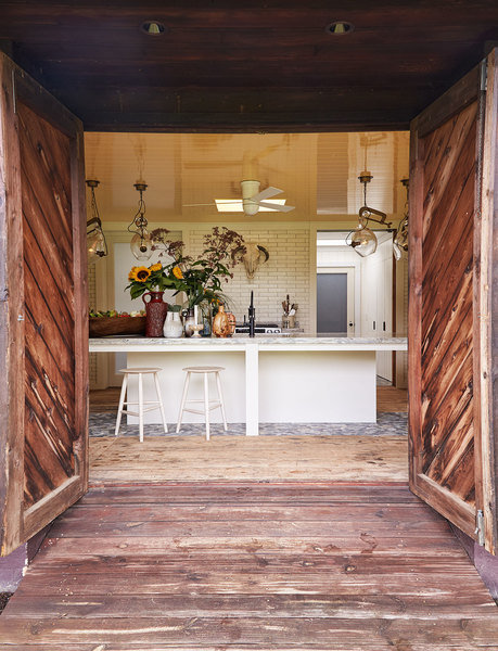 Weathered barn doors and flooring give a sense of history to a more modern kitchen designed by Philli